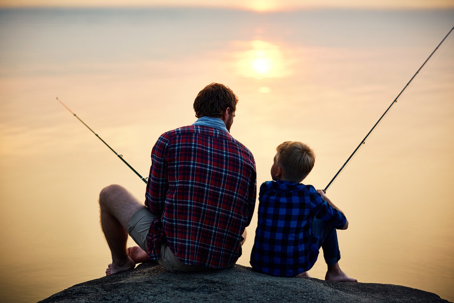 campground - Father and son sitting back to back fishing-iStock-599779866