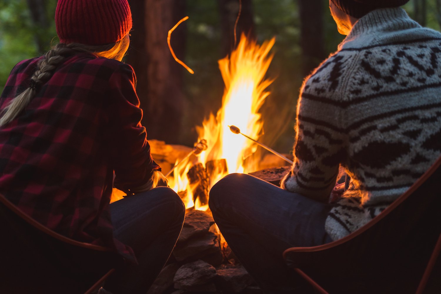 campground - couple young people fire camping fireside GettyImages-1178217558